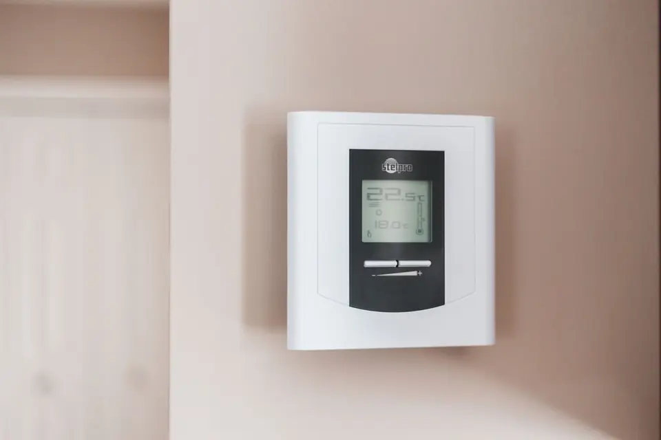 White wall-mounted digital thermostat showing a room temperature of 22.5C and a set point of 18.0C