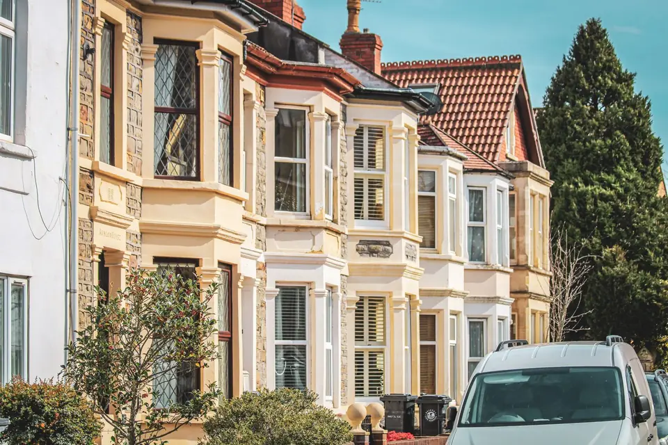 Bay-fronted terraced houses on a sunny street in Bristol with a white van parked outside