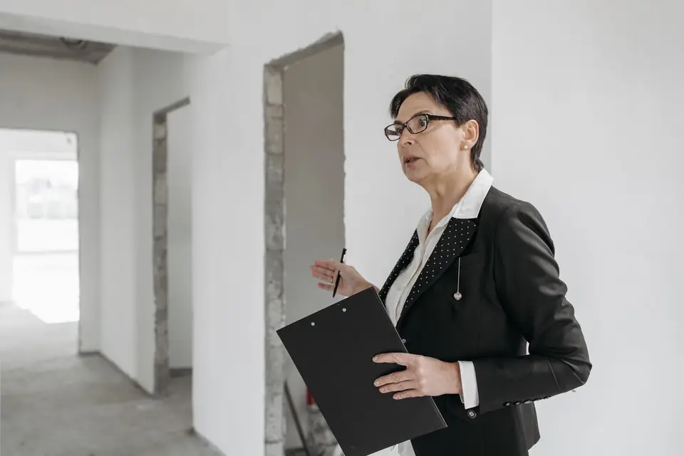 An assessor with a clipboard recording details in an empty room of a house
