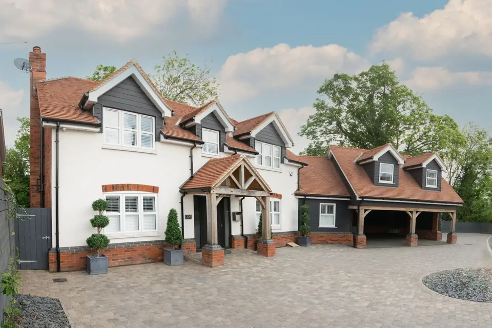 Large white rendered detached house with clay tile roof, oak porch, double carport and block paved driveway