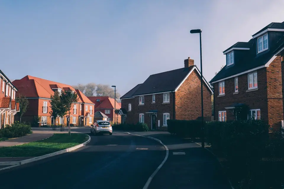 Red-brick detached and terraced houses along a curving road on a new-build housing estate