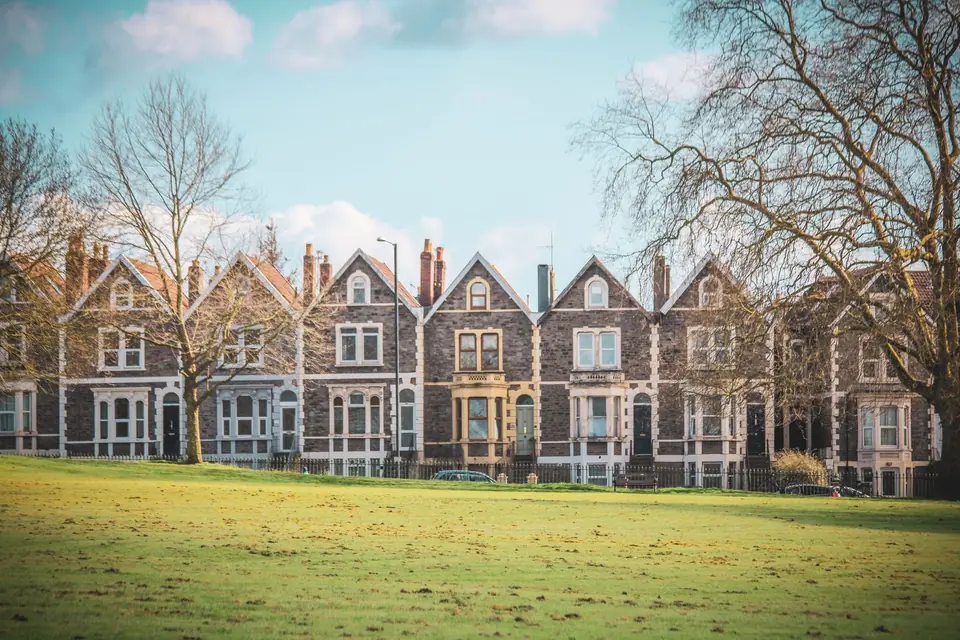 Row of Victorian gabled terraced houses with bay windows and chimneys facing a park lawn in Bristol