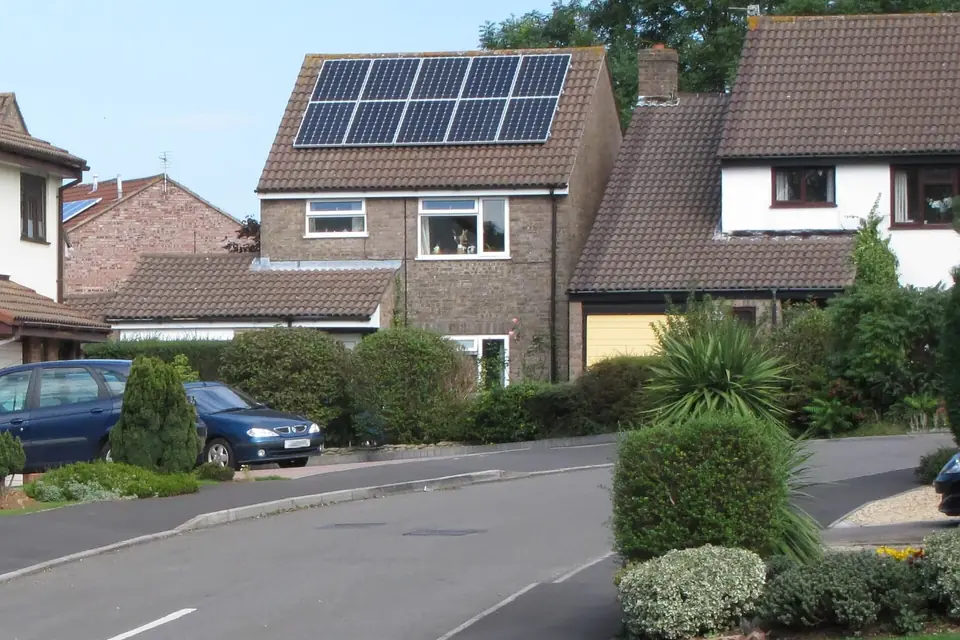 Ten solar panels on the tiled roof of a brick detached house on a suburban street in Yate, England